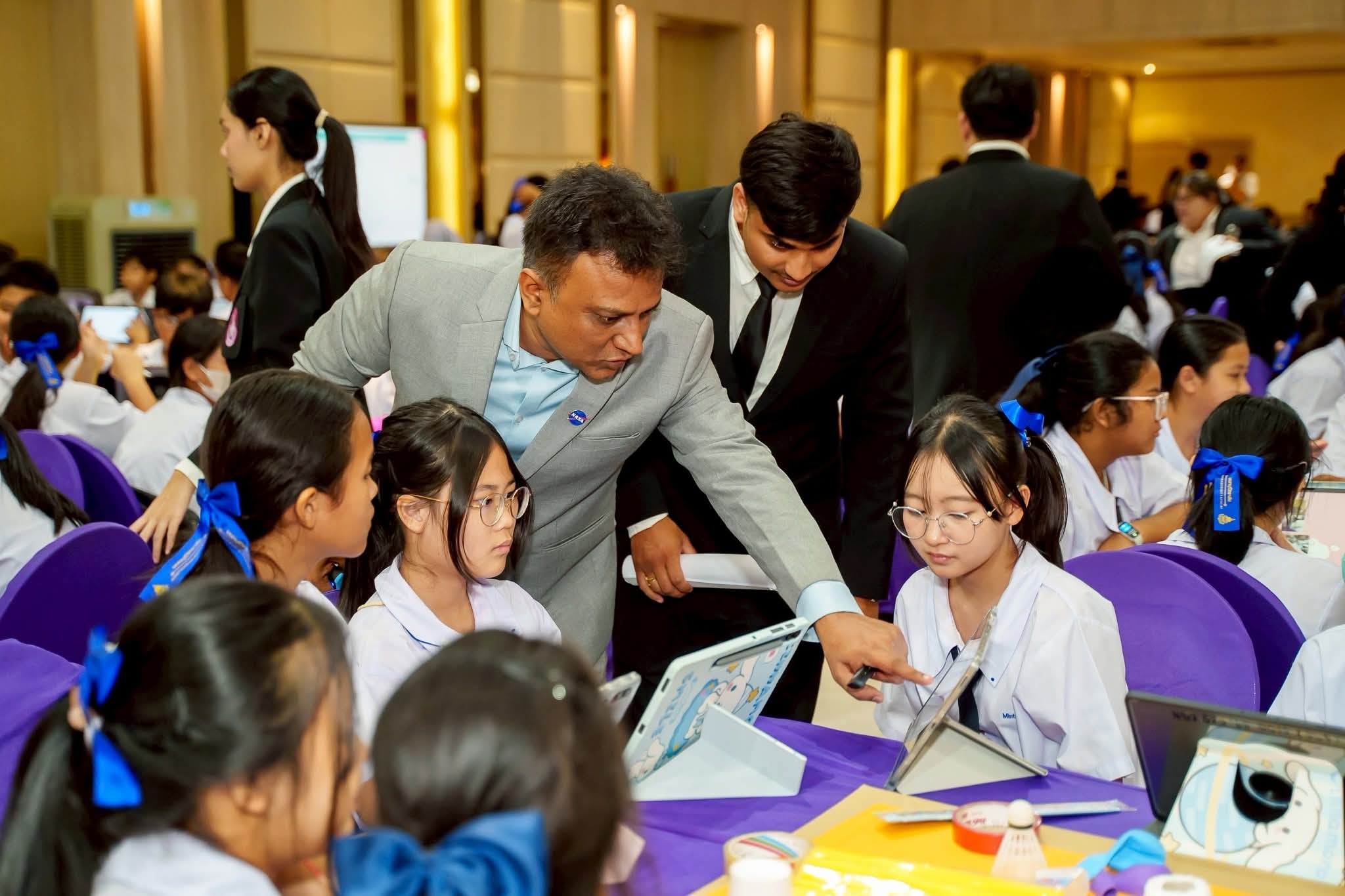 STEM কার্যক্রমে ট্যাবলেট নিয়ে কাজ করতে শিক্ষার্থীদের সাহায্য করছেন একজন পরামর্শদাতা