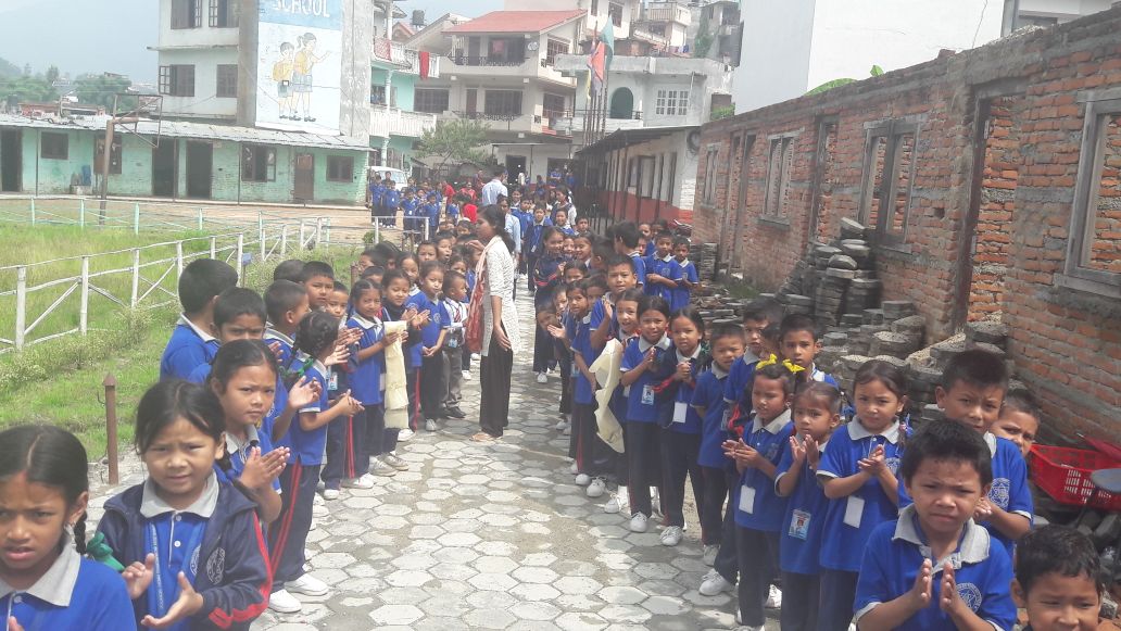 Anak-anak sekolah menyambut pengunjung di sepanjang jalan setapak