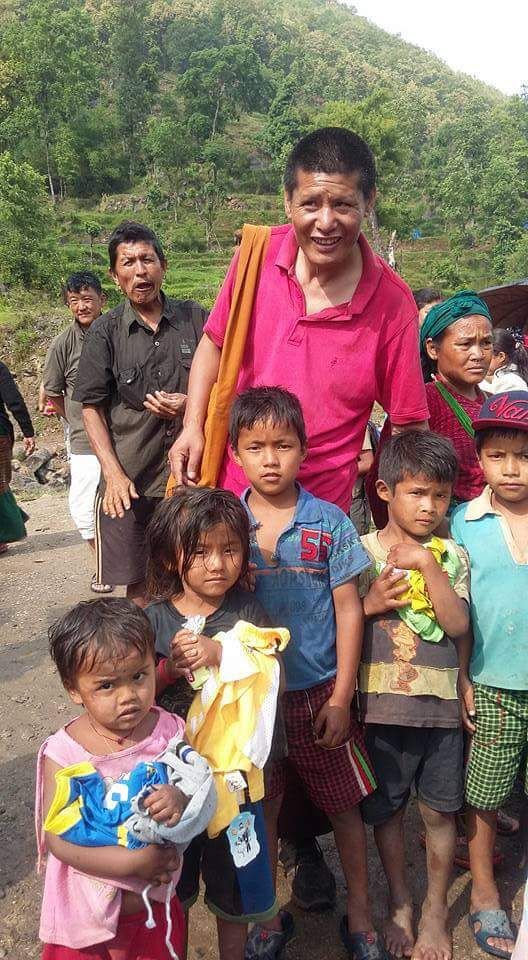 Orang dewasa berdiri bersama anak-anak yang memegang pakaian di luar ruangan