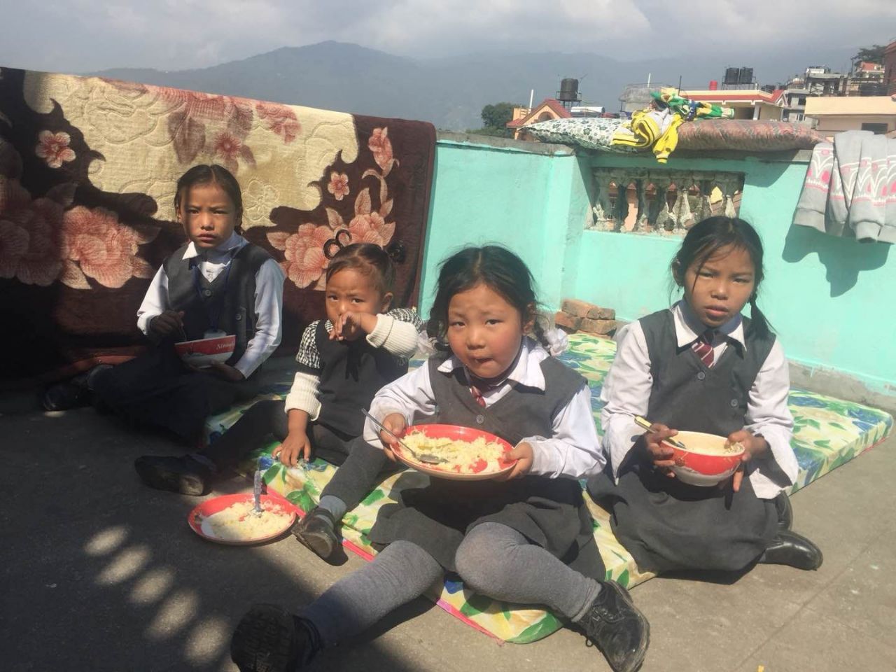 Anak-anak berseragam sekolah makan di luar ruangan